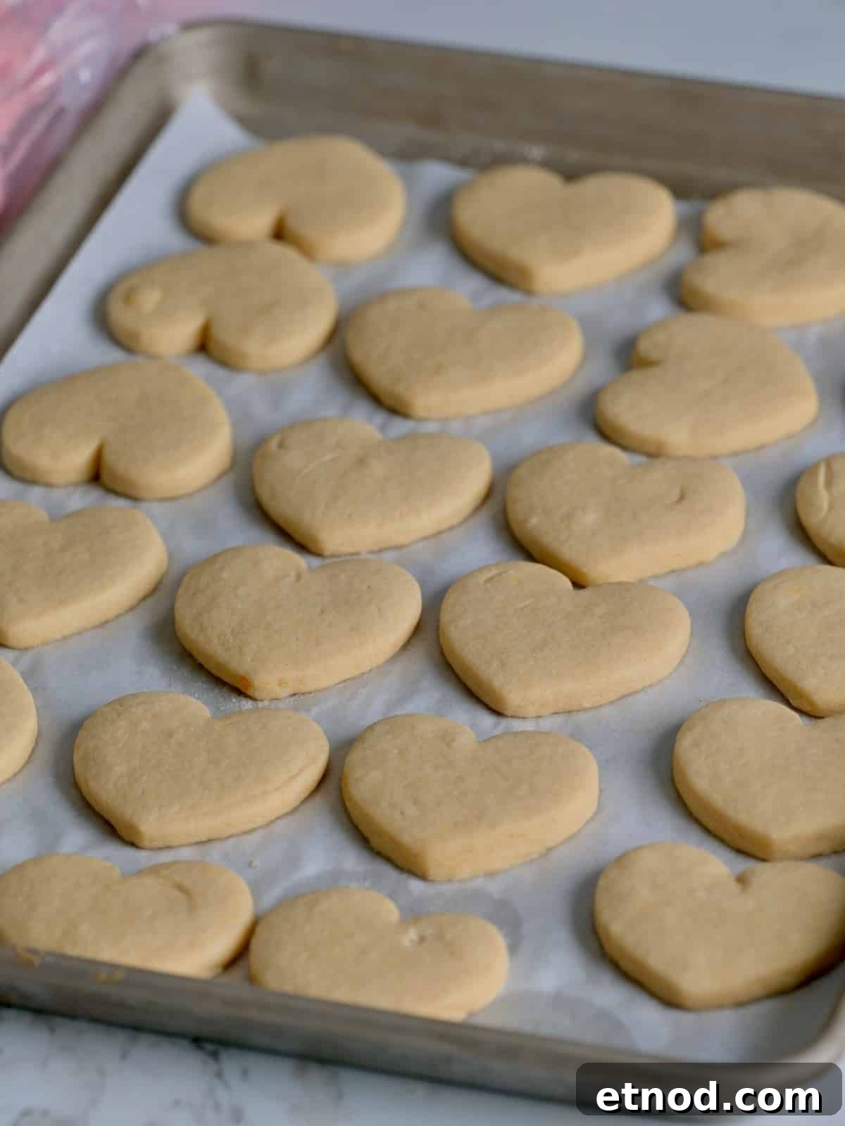 Valentine Sugar Cookies with Creamy Buttercream Frosting 8 Thick soft heart sugar cookies on a baking tray.