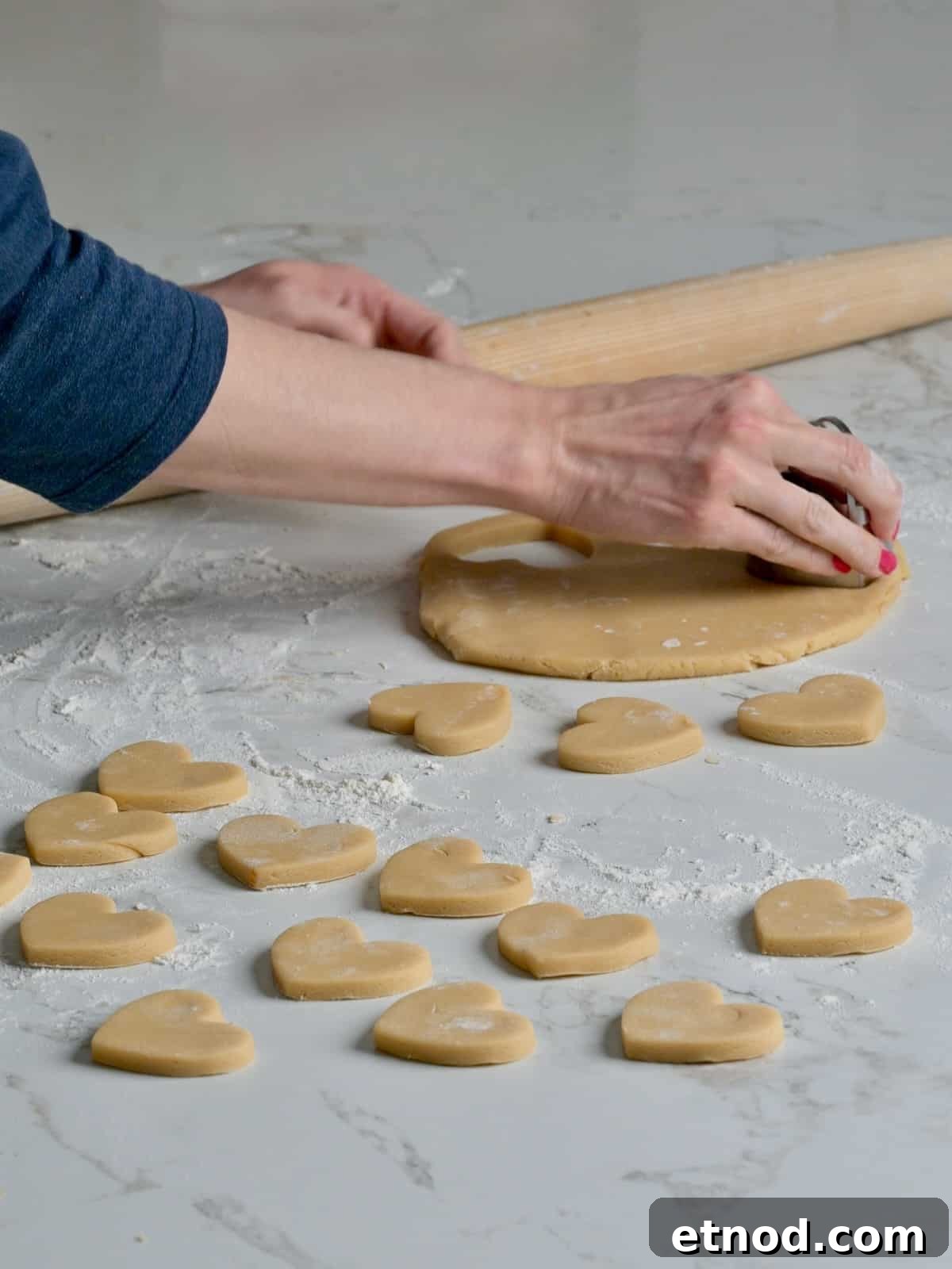 Valentine Sugar Cookies with Creamy Buttercream Frosting 6 Rolled out sugar cookie dough and heart cookie shapes being cut out of the dough.