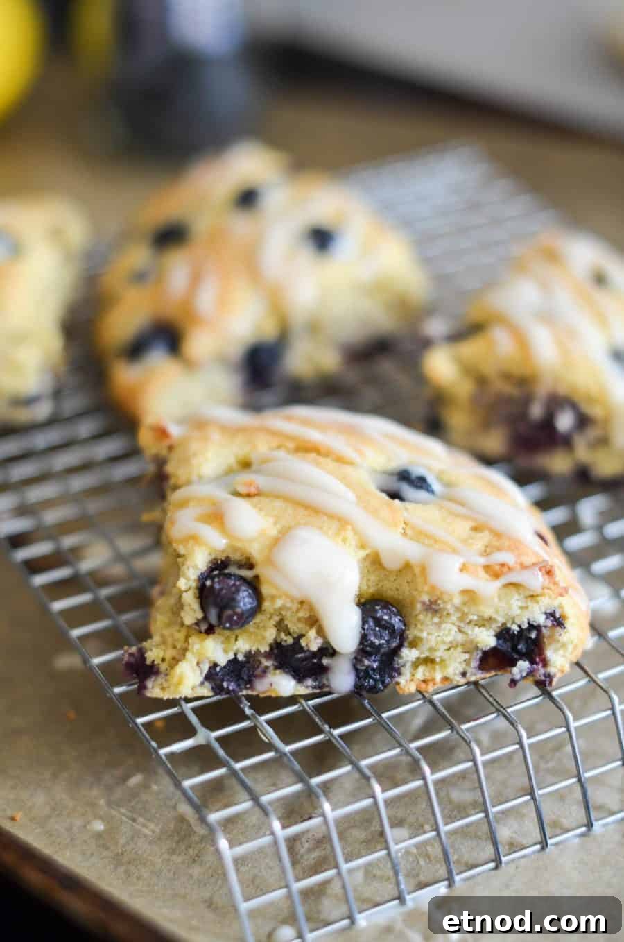 Close-up of blueberry scones with white icing drizzled on top, cooling on a metal wire rack—perfect for make ahead breakfast recipes.