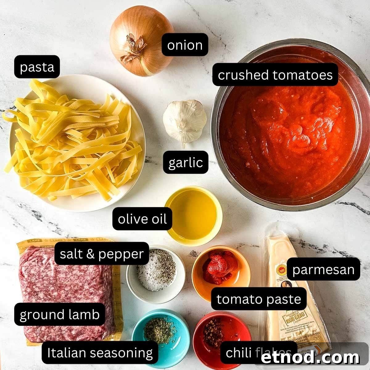labeled ingredients for slow cooker lamb ragu on a white marble counter.