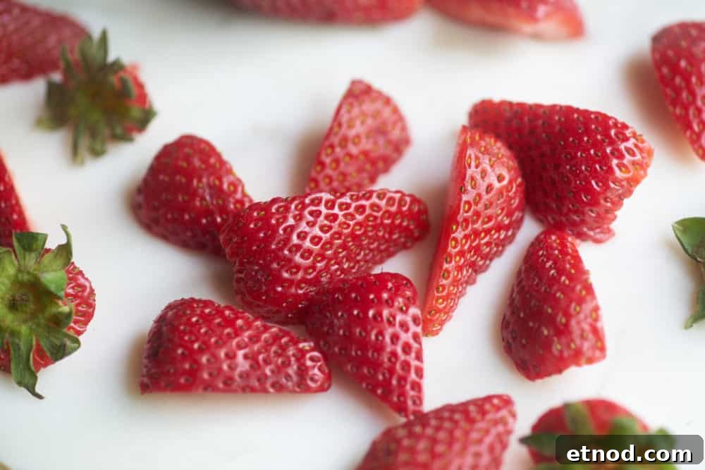Fresh strawberry slices on a marble cutting board.