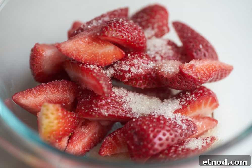 Fresh strawberries dusted with sugar in a glass bowl.