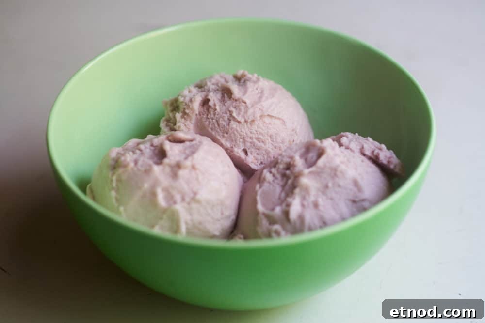 A bowl of dairy-free strawberry frozen dessert in a green plastic bowl.