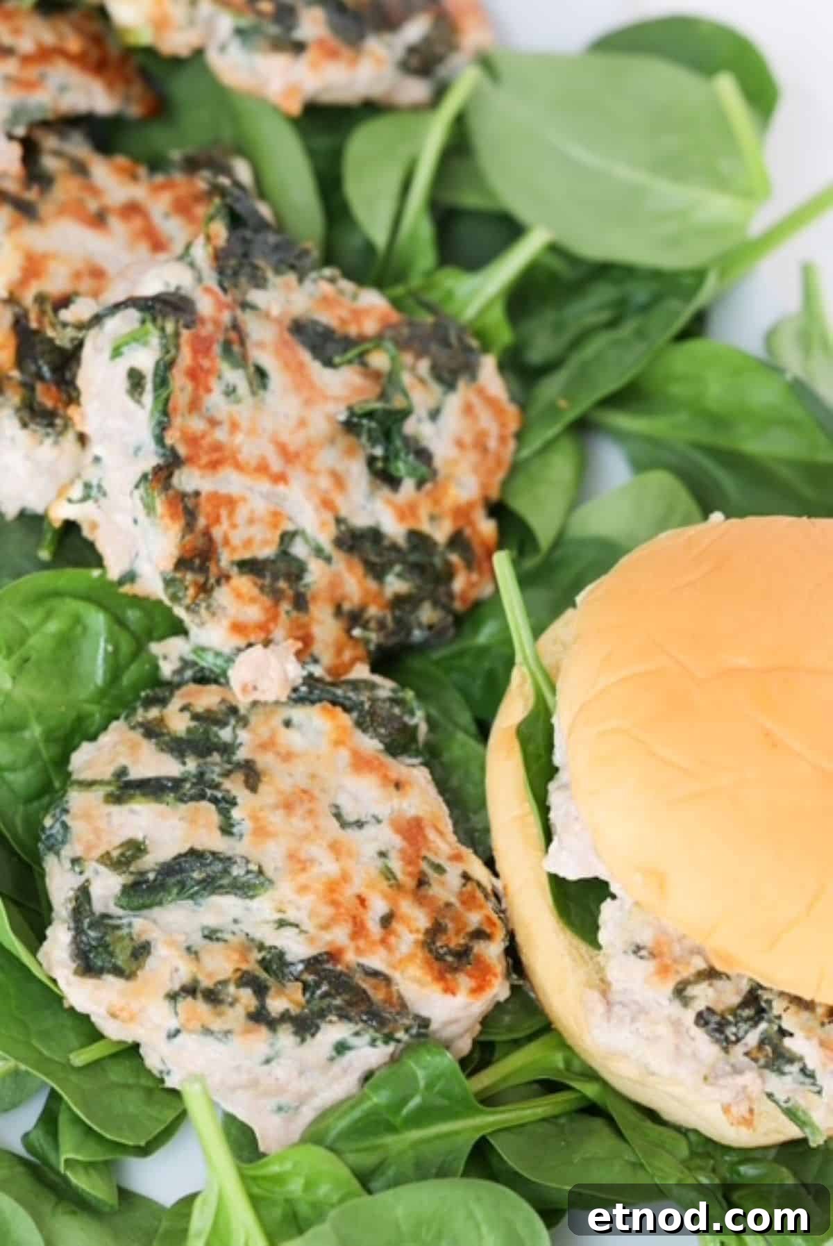 Feta & Spinach Turkey Burgers with Garlic Yogurt Sauce 2 Turkey burgers with spinach and feta cheese on a bed of baby spinach and one burger in a burger roll.