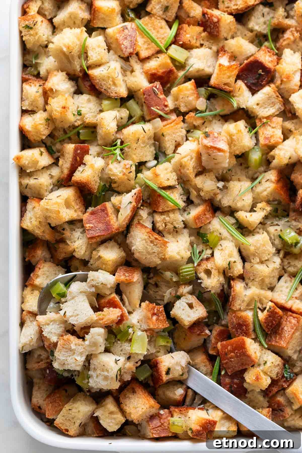 Vegan stuffing in a baking dish with a serving spoon.