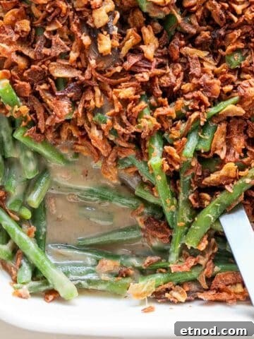Baking dish of vegan green bean casserole with a serving spoon.