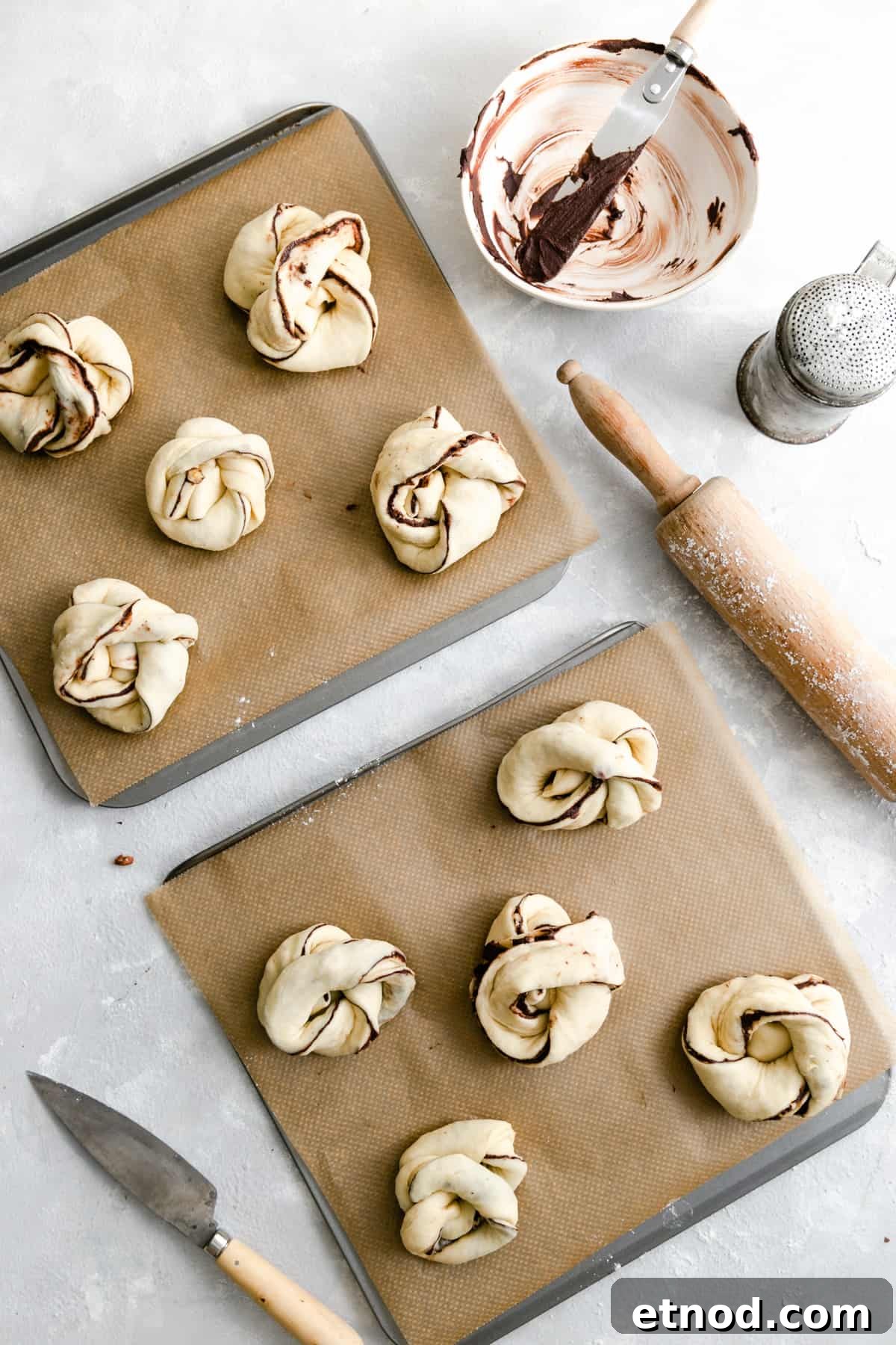 Chocolate Hazelnut Babka Buns Recipe with Gooey Swirls 8 Overhead shot of two baking sheets with unbaked chocolate hazelnut babka buns ready for the oven