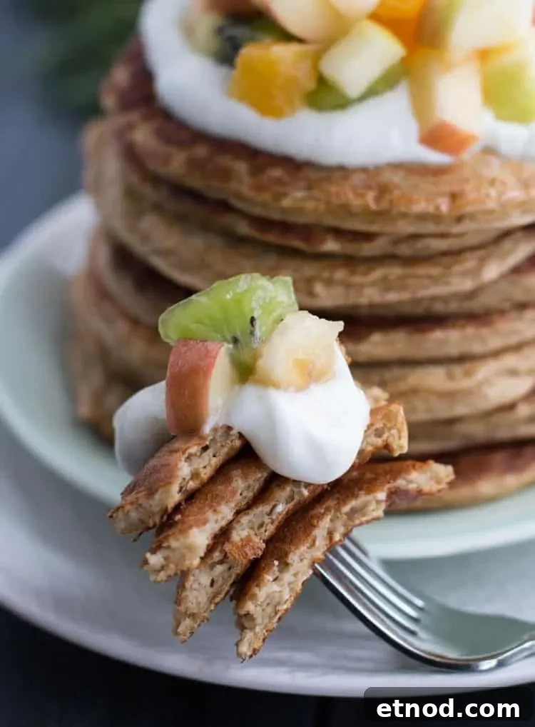 Protein-Packed Oatmeal & Cottage Cheese Pancakes for Muscle Fuel 9 Oatmeal Cottage Cheese Protein Pancakes on a fork with mixed fruit from themerchantbaker.com