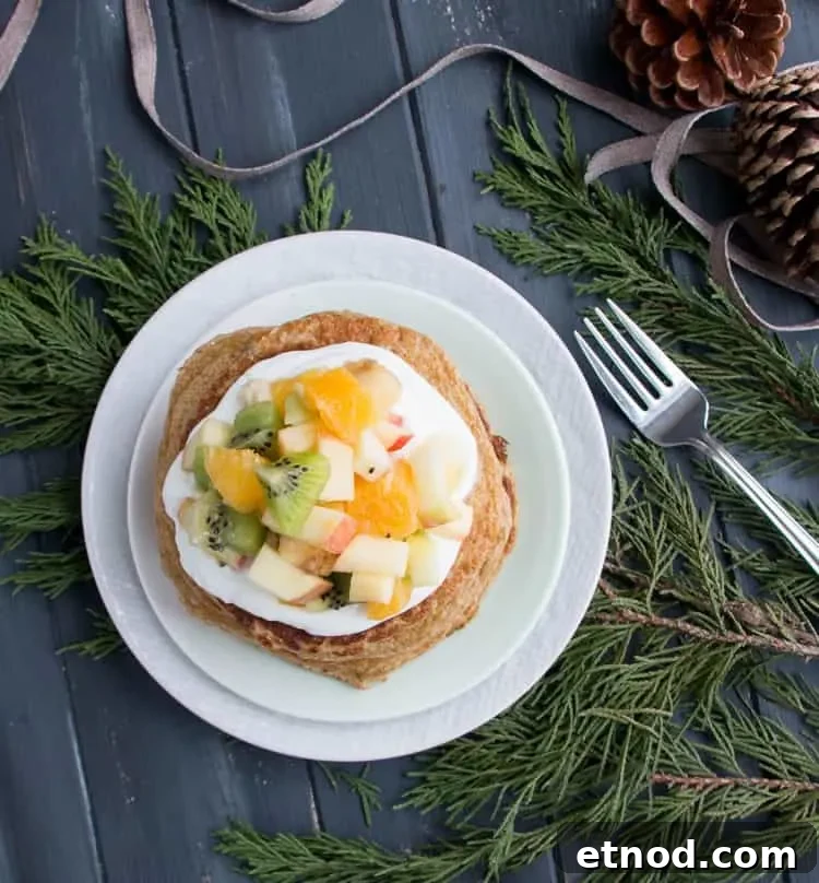 Protein-Packed Oatmeal & Cottage Cheese Pancakes for Muscle Fuel 3 A top view of Oatmeal Cottage Cheese Protein Pancakes on a plate topped with mixed fruit from themerchantbaker.com