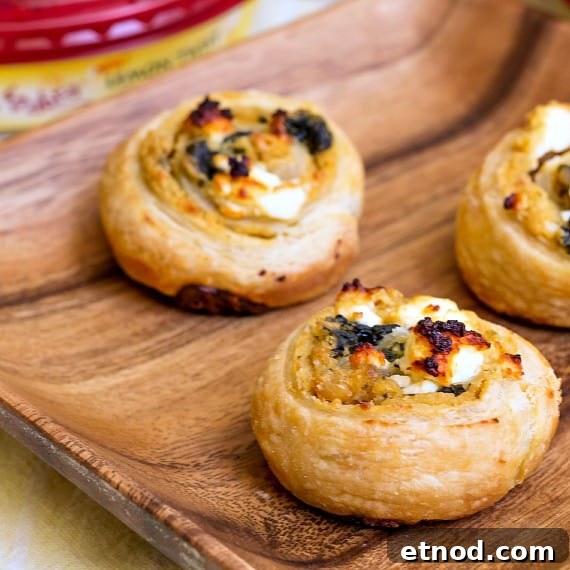 Spinach and Feta Hummus Pinwheels: Party Appetizer 6 2 hummus pinwheels made with spinach and feta cheese on a wooden plate.