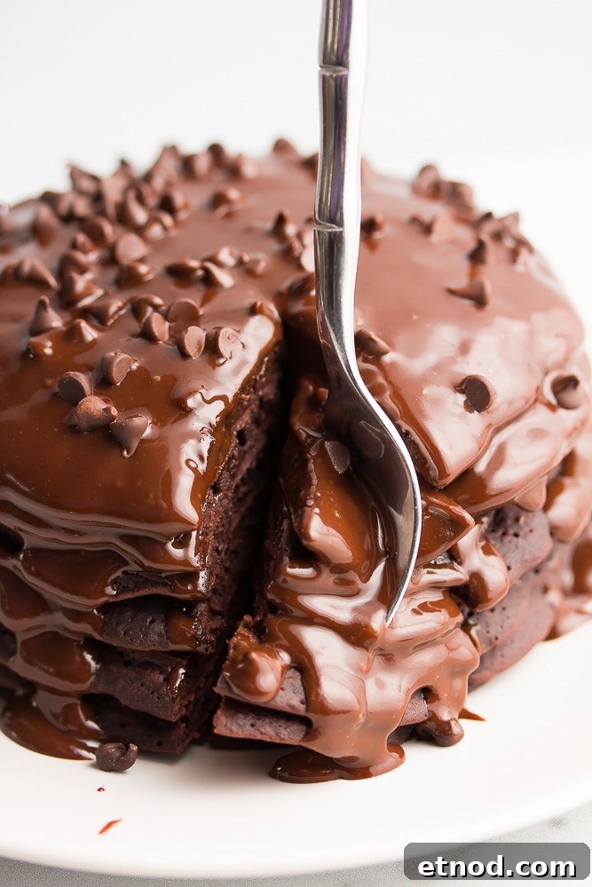 Fluffy Vegan Chocolate Pancakes Recipe for Rich, Dairy-Free Indulgence 3 fork taking a bit from a stack of chocolate pancakes