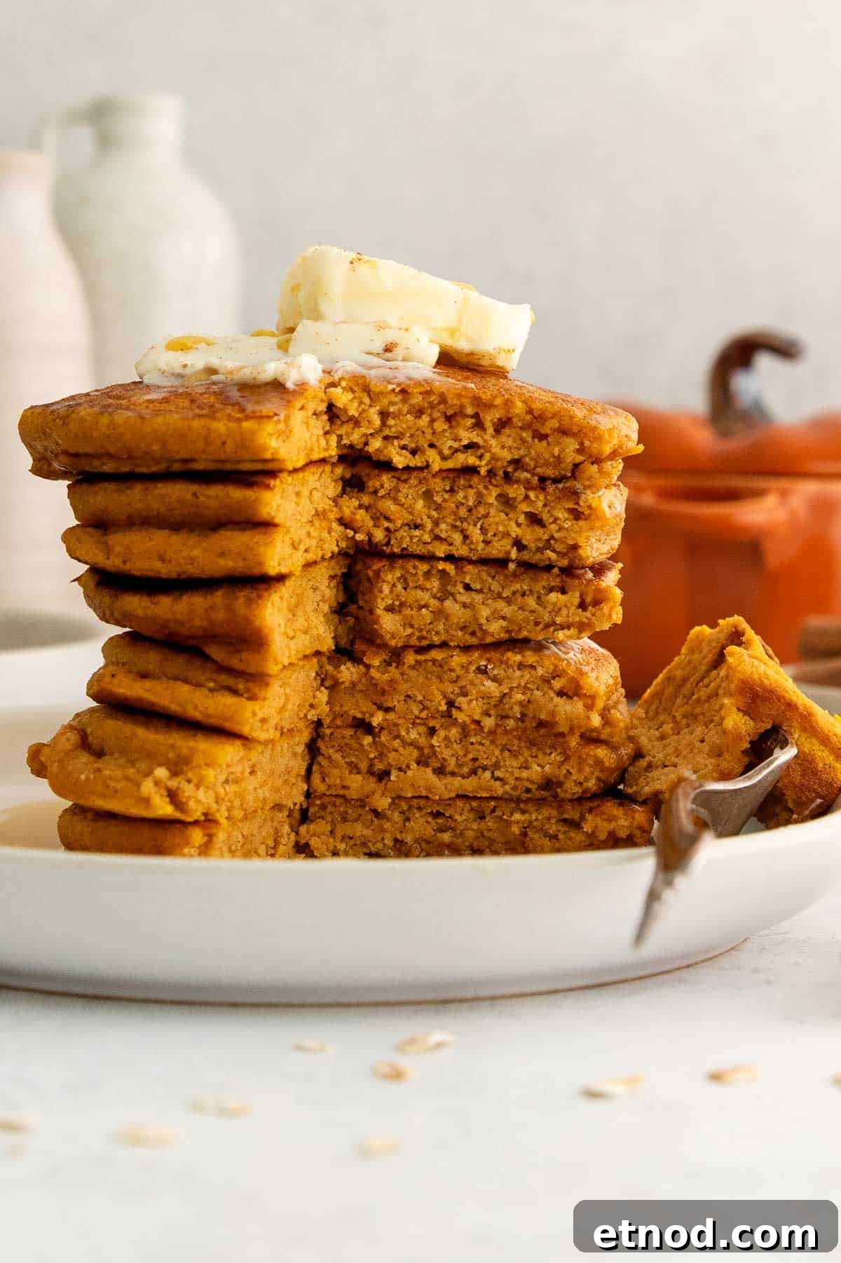 stack of oat flour pumpkin pancakes with section cut out and bite on fork.