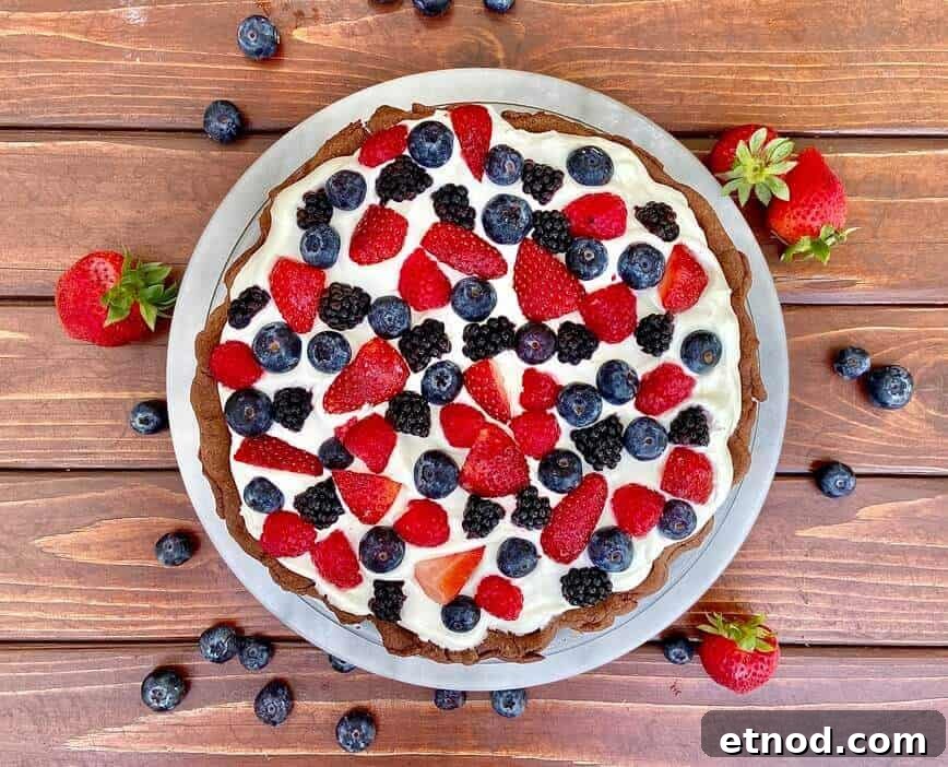Mixed Berry Cream Chocolate Pie Recipe 6 Whole pie on wood table, with berries sprinkled around.
