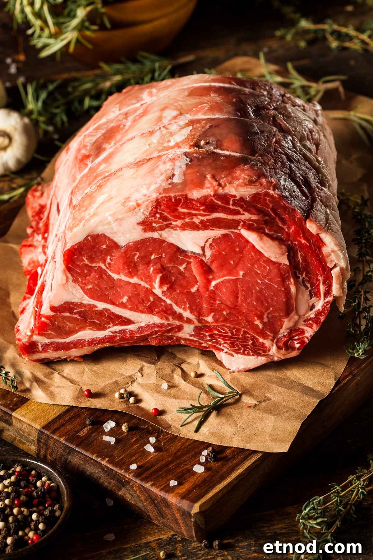 a standing rib roast on parchment paper on a cutting board, ready to be seasoned before going into the oven