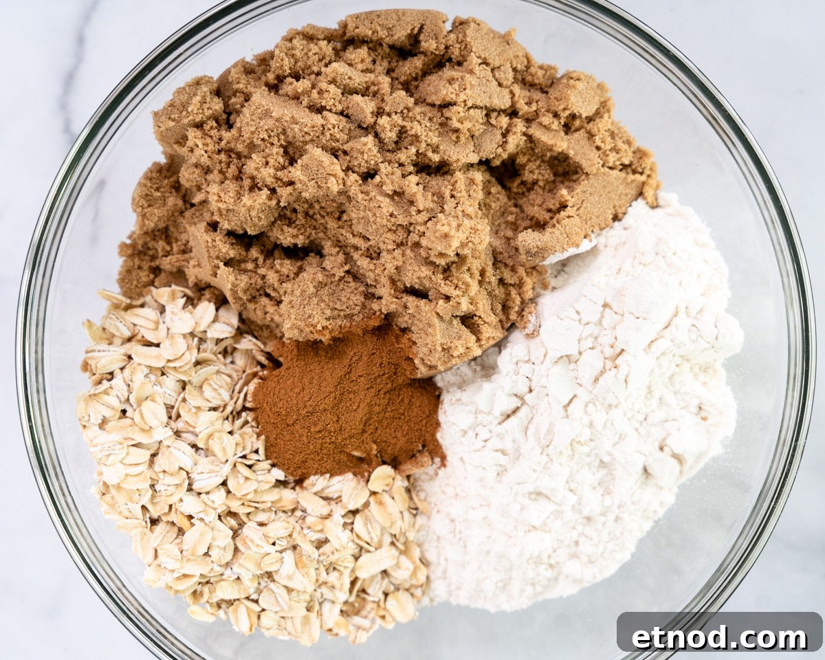Old-Fashioned Rhubarb Crunch Recipe — Classic Homestyle Dessert 6 Top down view of crunch topping ingredients in a bowl including flour, oats, cinnamon, and brown sugar. Hostess At Heart