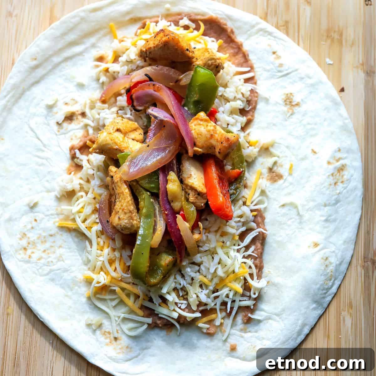 A tortilla with fajita filling inside on a cutting board.