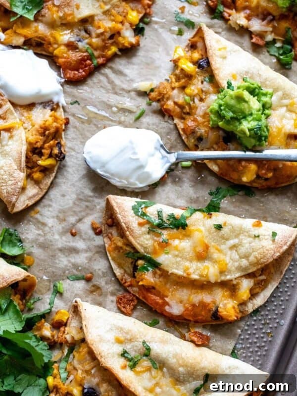 Crispy Chicken Tacos on a baking sheet with guacamole.