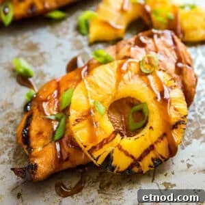 Hawaiian Aloha Chicken Recipe with Pineapple and Teriyaki Glaze 14 A piece of pineapple chicken breast with a grilled pineapple slice on a pan with other pieces behind it.