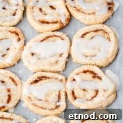 Glazed cinnamon roll cookies on parchment paper.