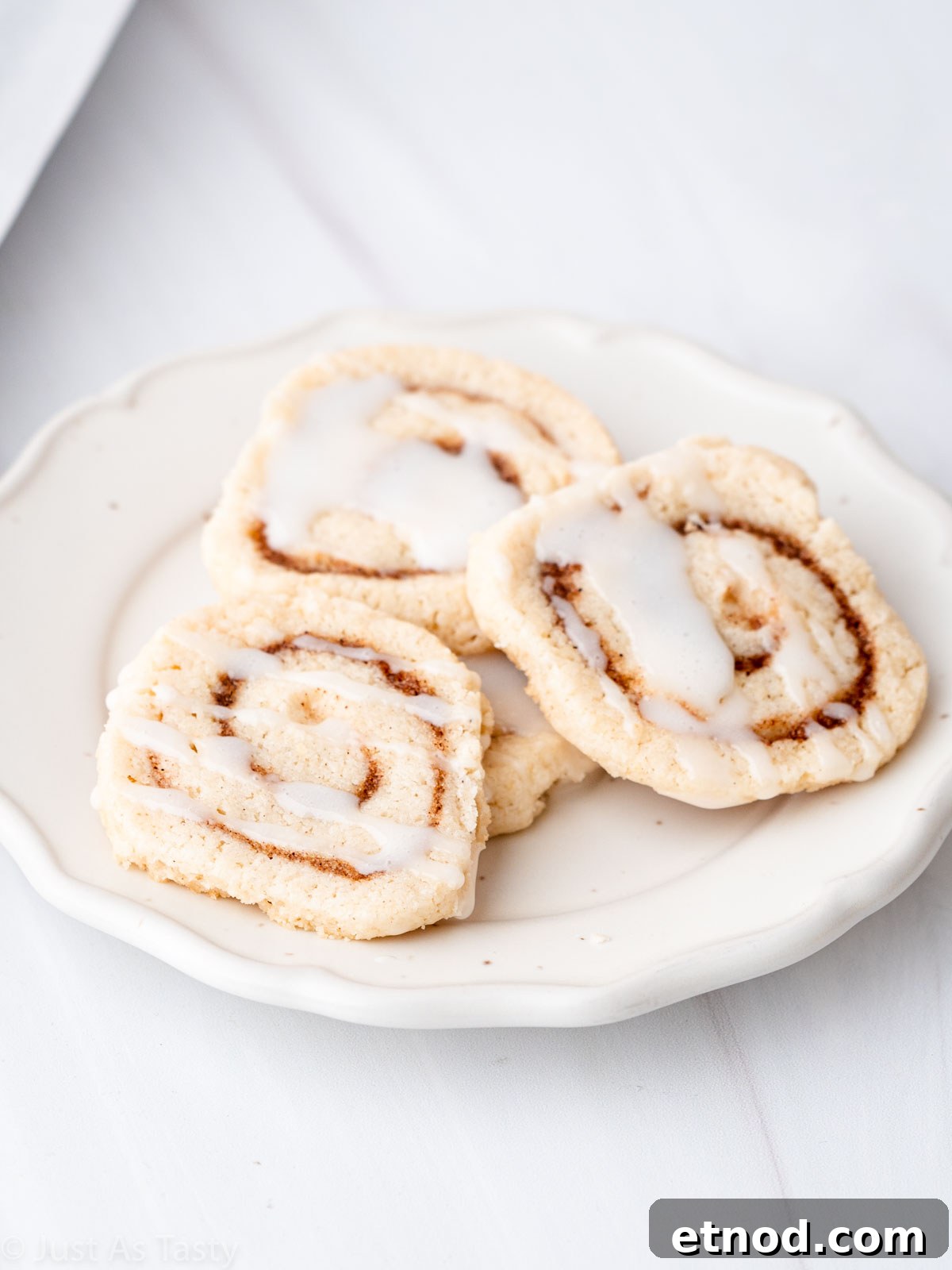 Glazed cinnamon roll cookies on a white plate.