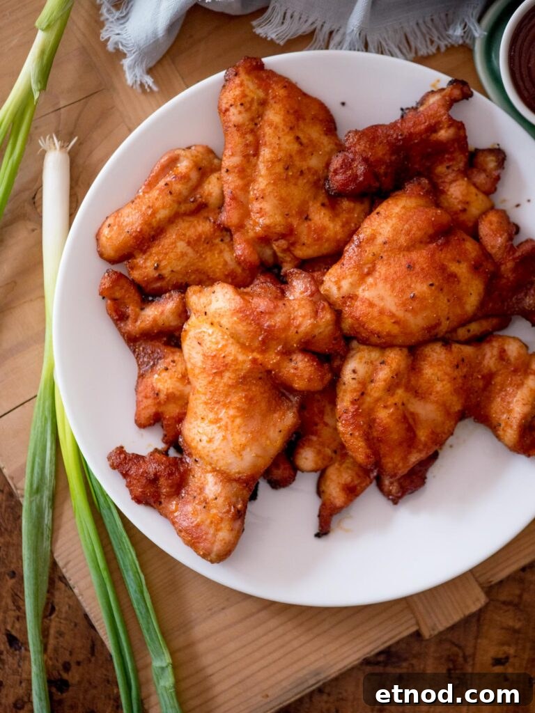 Juicy Chicken Thighs on a Pellet Grill: Flavorful Recipe Guide 2 Whole green scallions garnished next to a plate of smoked chicken thighs.