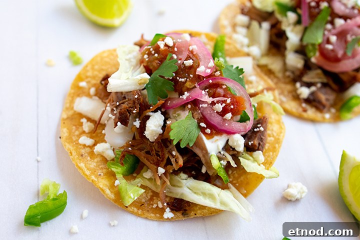 Crispy Instant Pot Carnitas Recipe for Authentic Mexican Flavor 11 Close up of carnitas tacos on white background with limes.