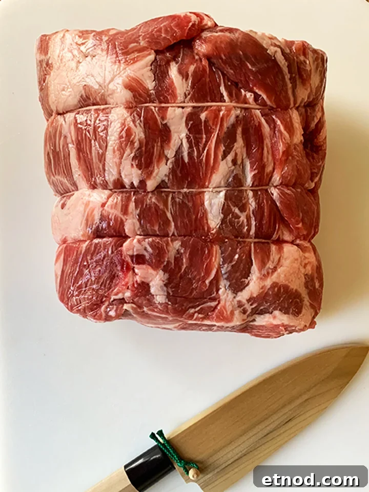 Crispy Instant Pot Carnitas Recipe for Authentic Mexican Flavor 3 A whole pork butt on cutting board with knife.