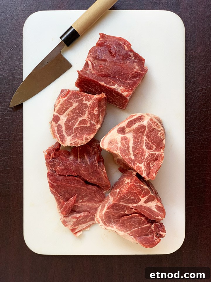 Crispy Instant Pot Carnitas Recipe for Authentic Mexican Flavor 7 Chunks of pork roast on white cutting board with knife.
