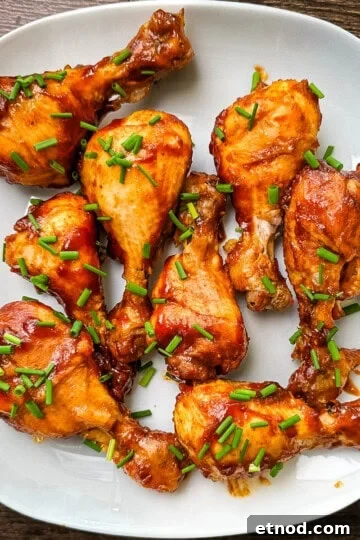Chicken legs cooked in the Instant Pot arranged on a white plate, garnished with fresh chives.