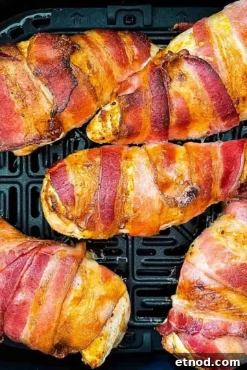 Cooked bacon-wrapped chicken in the air fryer basket.