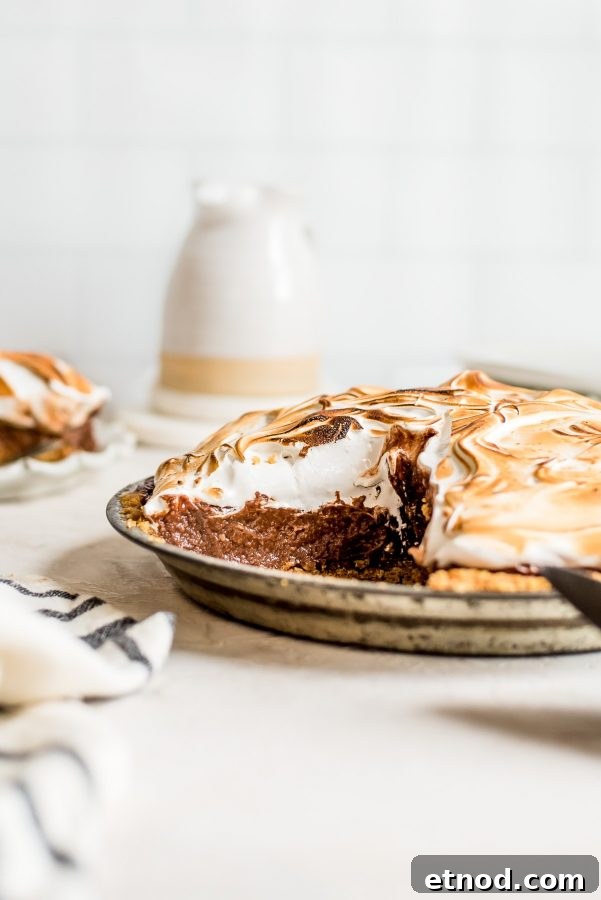 Decadent S'mores Pie Recipe with Chocolate Graham Cracker Crust 4 pie in pan with slice missing