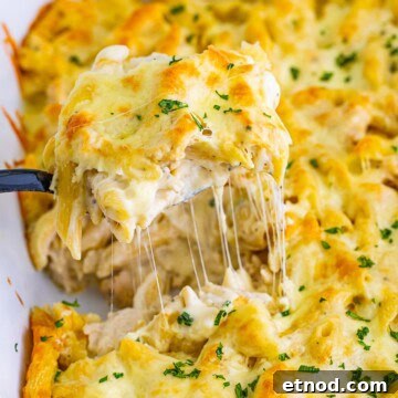 Creamy chicken alfredo bake with a cheese pull being lifted from the dish.