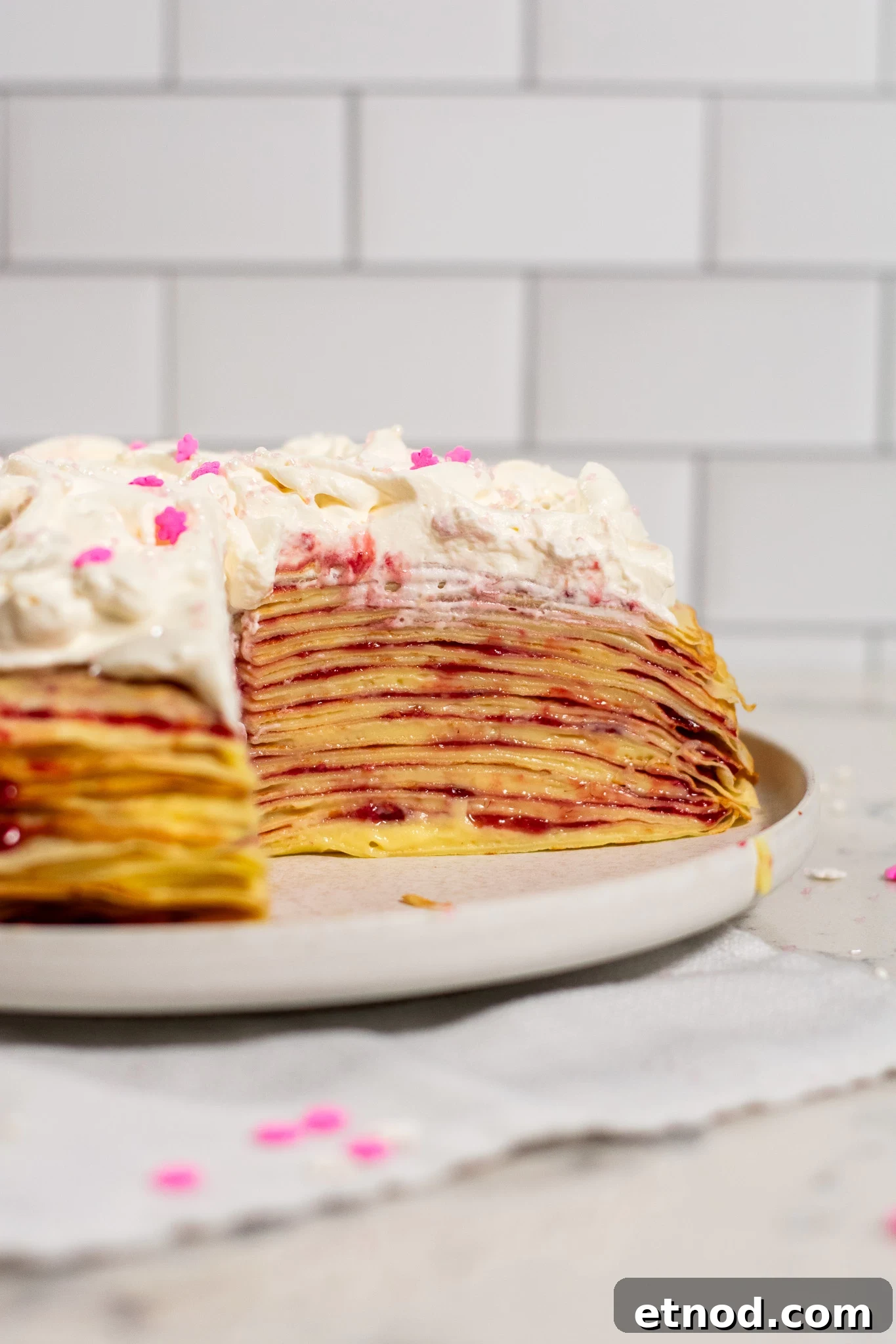 Vanilla and Raspberry Pancake Layer Cake Recipe 11 A cross section of a pancake layer cake with vanilla pastry cream and raspberry jam, topped with whipped cream.