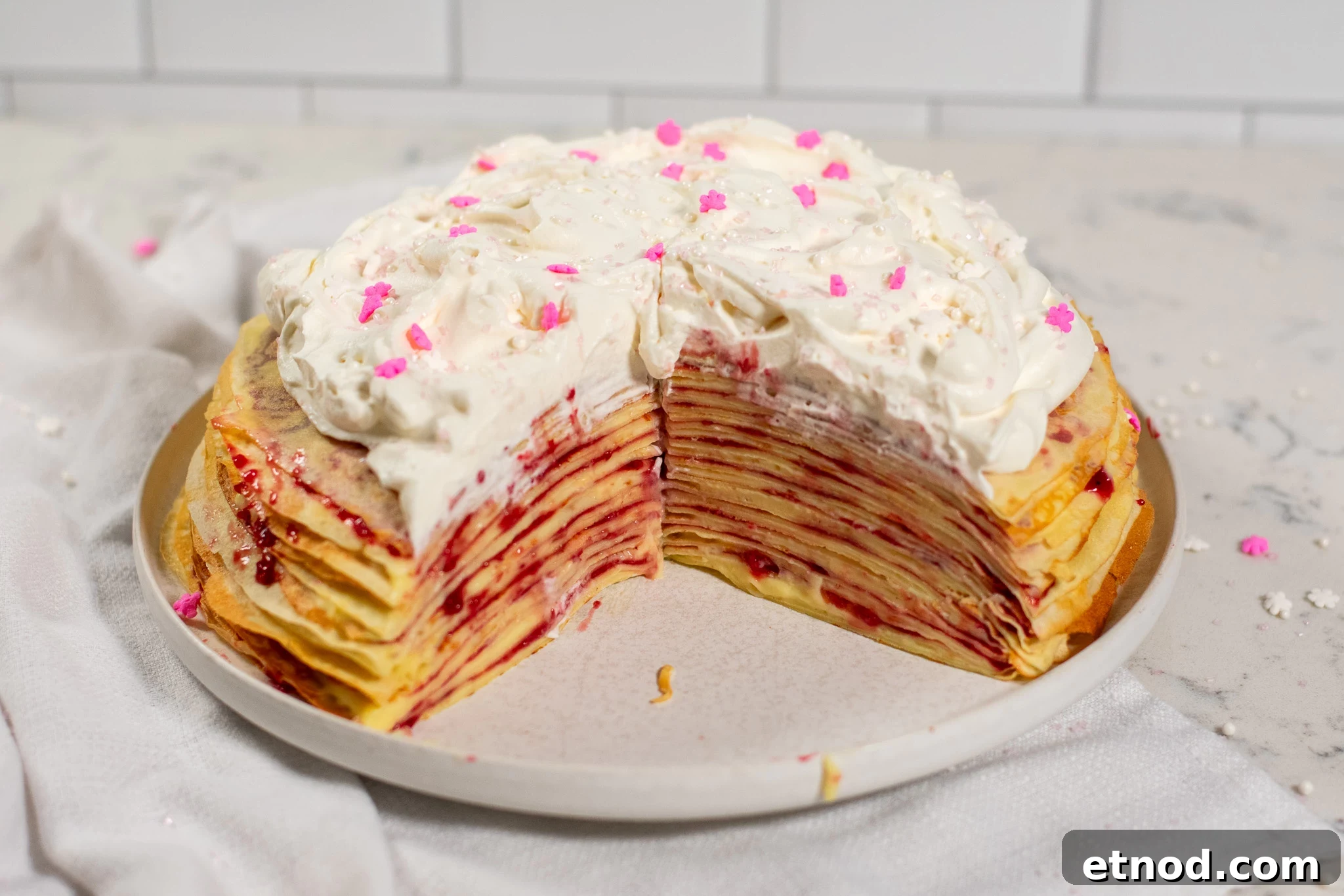 Vanilla and Raspberry Pancake Layer Cake Recipe 12 A cross section of a pancake layer cake with vanilla pastry cream and raspberry jam, topped with whipped cream.