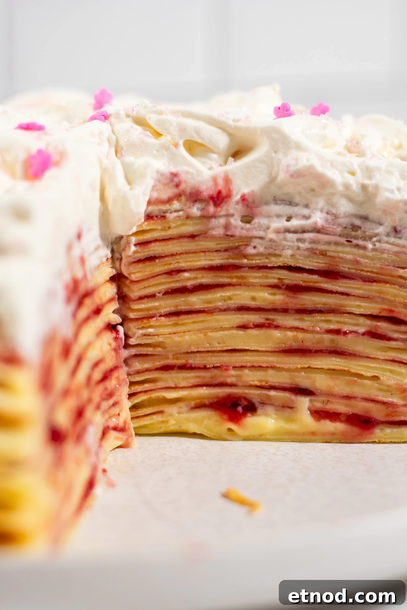 Vanilla and Raspberry Pancake Layer Cake Recipe 7 A cross section of a pancake layer cake with vanilla pastry cream and raspberry jam, topped with whipped cream.