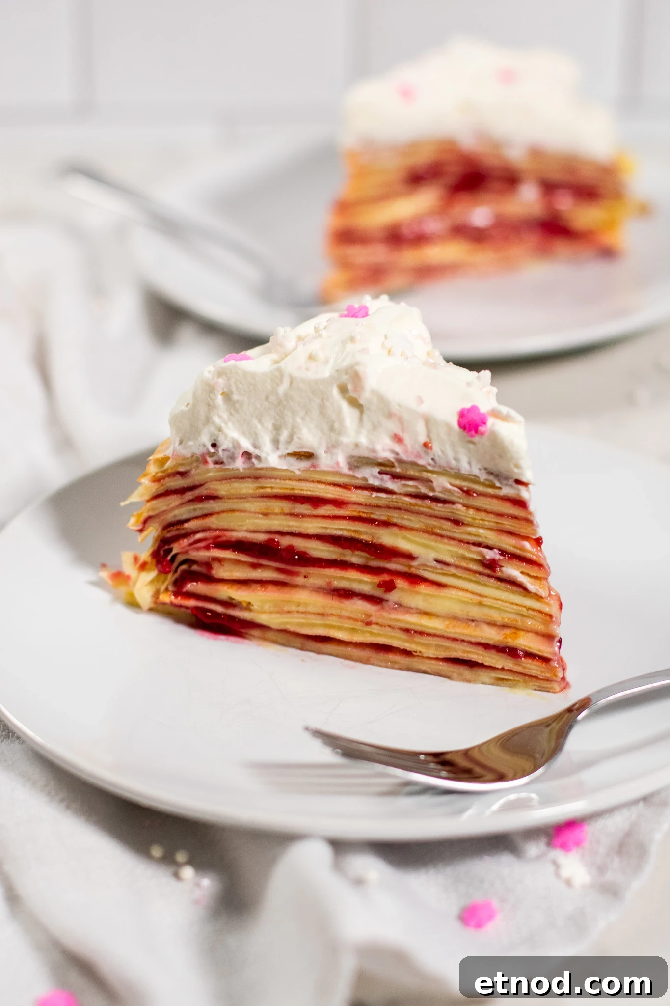 Vanilla and Raspberry Pancake Layer Cake Recipe 8 A slice of pancake layer cake with vanilla pastry cream and raspberry jam, topped with whipped cream.