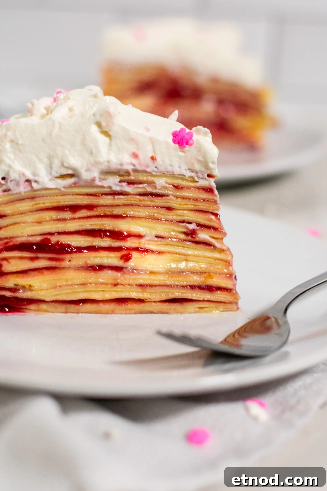 Vanilla and Raspberry Pancake Layer Cake Recipe 9 A slice of pancake layer cake with vanilla pastry cream and raspberry jam, topped with whipped cream.