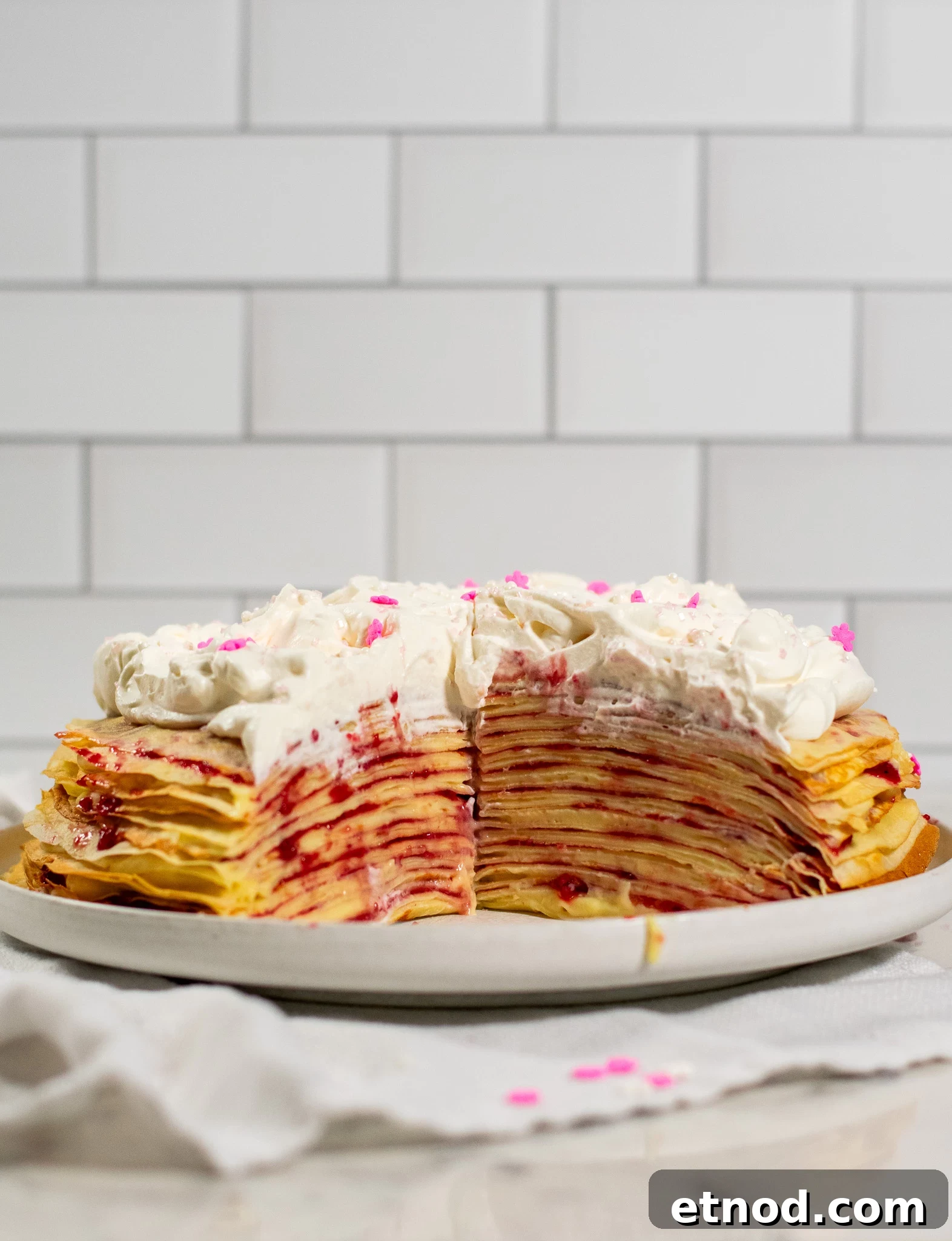 Vanilla and Raspberry Pancake Layer Cake Recipe 10 A cross section of a pancake layer cake with vanilla pastry cream and raspberry jam, topped with whipped cream.
