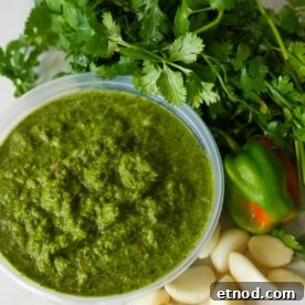 Authentic Puerto Rican Sofrito Recipe for Flavorful Dishes 8 Puerto Rican Sofrito recipe in a container close up with peppers and garlic on the side.