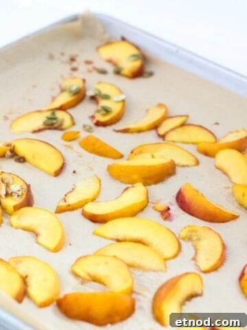 Roasted peach slices on a lined baking sheet.