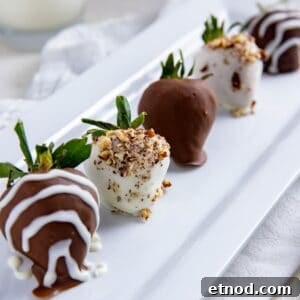 Chocolate covered strawberries with white chocolate drizzle and chopped pecans on a rectangular white serving platter.