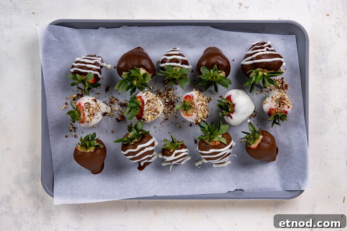 Ten chocolate dipped and decorated strawberries on parchment lined cookie sheet.
