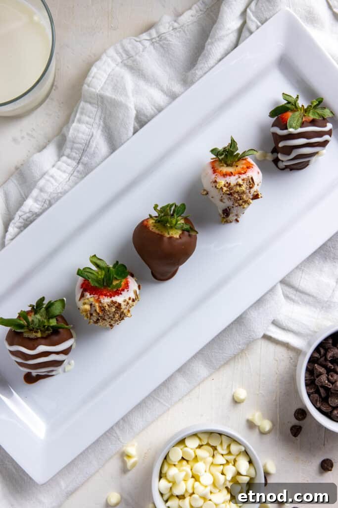 Chocolate covered strawberries with white chocolate drizzle and chopped pecans on a rectangular white serving platter.