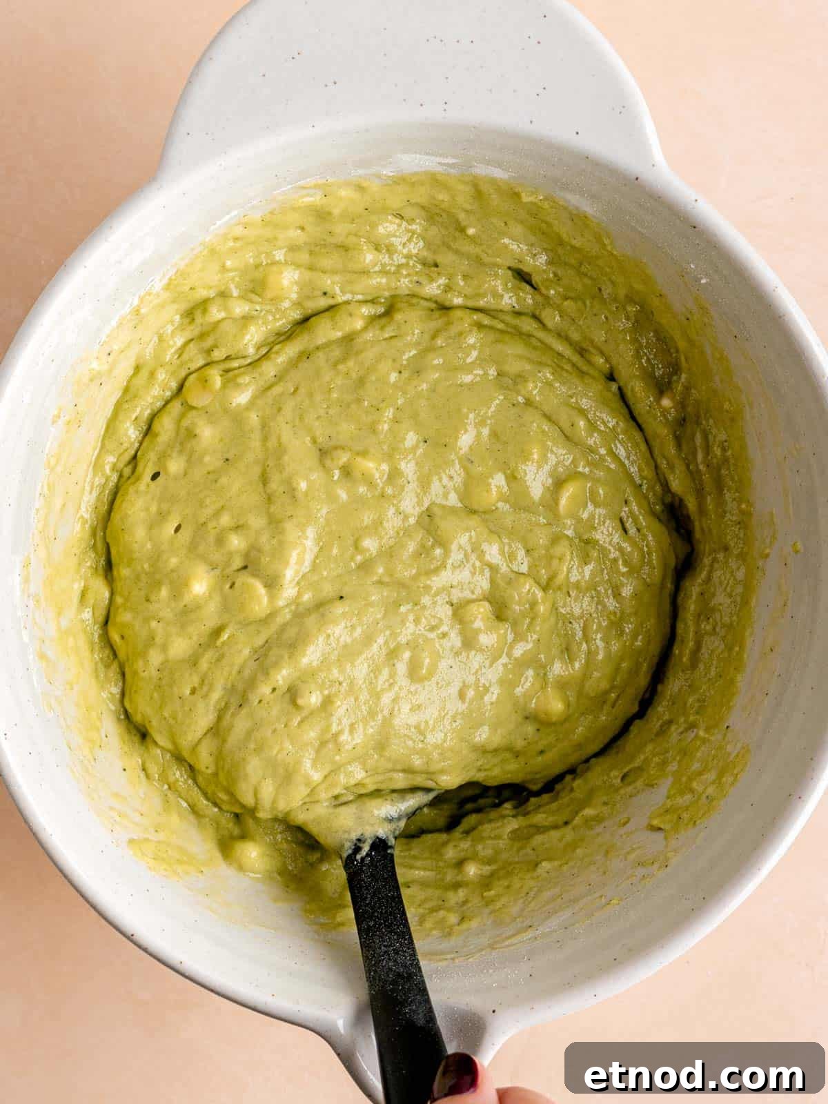 Matcha Muffins with White Chocolate Chips: Soft & Moist Recipe 6 Folding matcha muffin batter with white chocolate chips in a bowl.