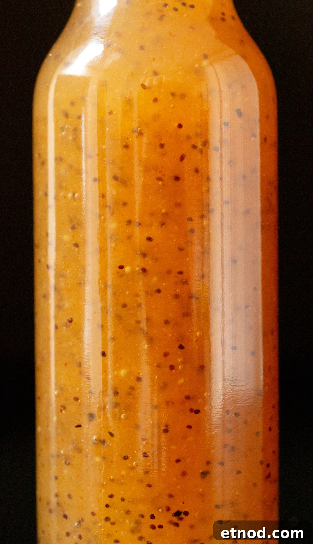 Subway Sweet Onion Sauce: Flavor, Ingredients & How It's Made 3 Close up of a glass bottle filled with brown subway sweet onion sauce. You can see the poppyseeds suspended throughout the sauce.