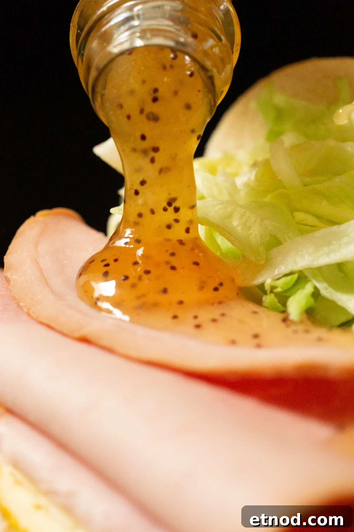 Subway Sweet Onion Sauce: Flavor, Ingredients & How It's Made 5 Copycat sweet onion sauce being poured out of the bottle onto a ham sandwich.
