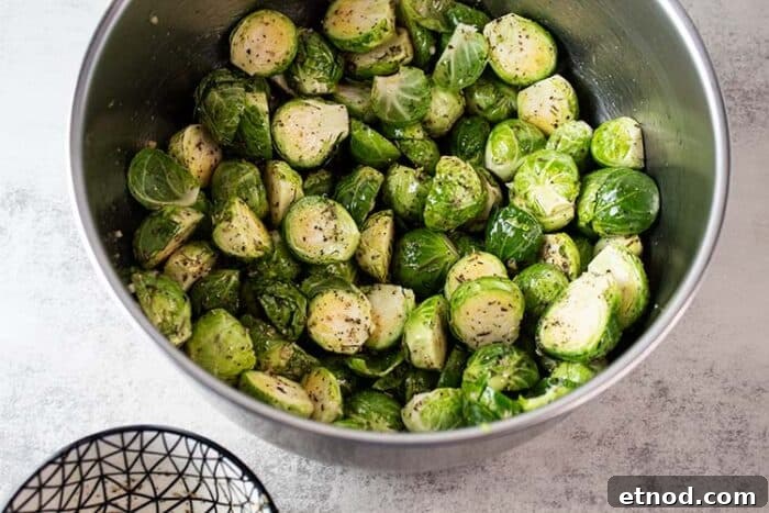 Oven-Roasted Keto Brussels Sprouts Recipe 4 overhead view of metal mixing bowl with brussel sprouts with olive oil added