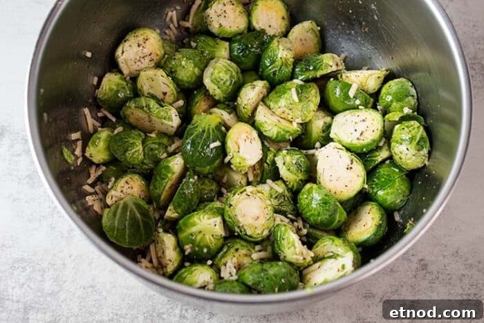 Oven-Roasted Keto Brussels Sprouts Recipe 5 overhead view of metal mixing vowl of brussel sprouts with olive oil and seasoning added for mixing