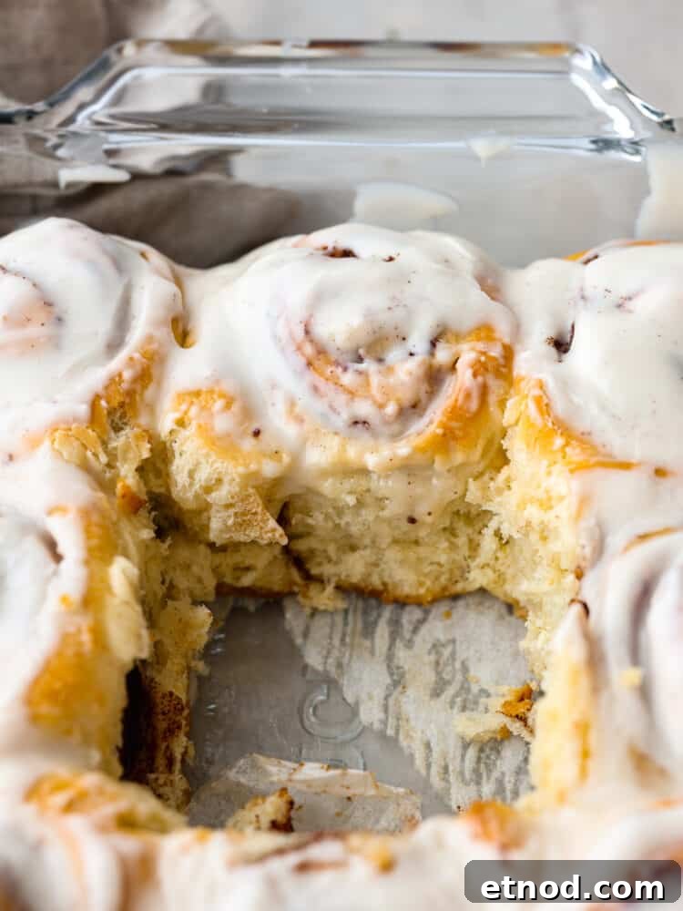 Cinnamon rolls in a baking pan A pan with cinnamon rolls with one roll that is taken out.