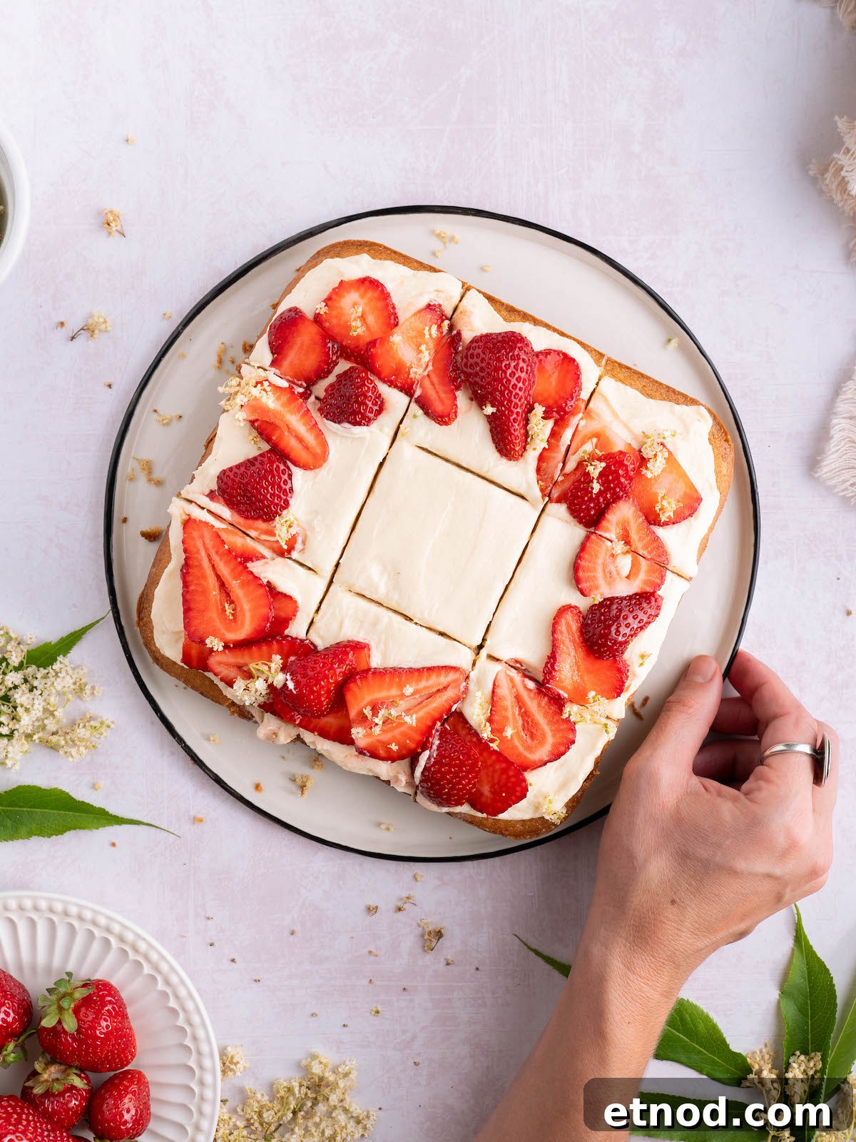 A square cake with strawberries on top, sliced into 9 pieces